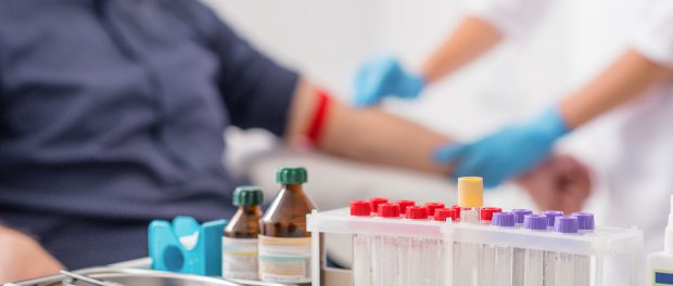 Doctor preparing patient for blood sampling. Focus on blood test tools on table